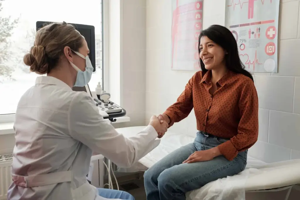 A masked clinician talking with a patient in an exam room